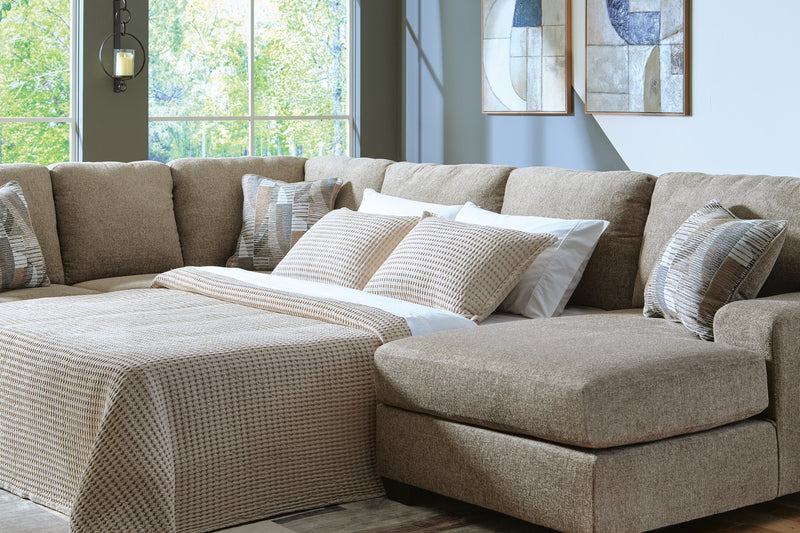 Ashley Furniture Newellen Sleeper Sectional with chaise, gray fabric, featuring plush cushions and a built-in sleeping area.