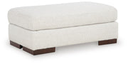 Ashley Furniture Hartside Ottoman with upholstered fabric and wooden block feet, shown from an angle.