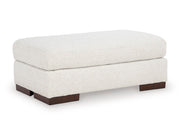 Ashley Furniture Hartside Ottoman with soft fabric upholstery, shown from a side angle in a spacious living room setting.