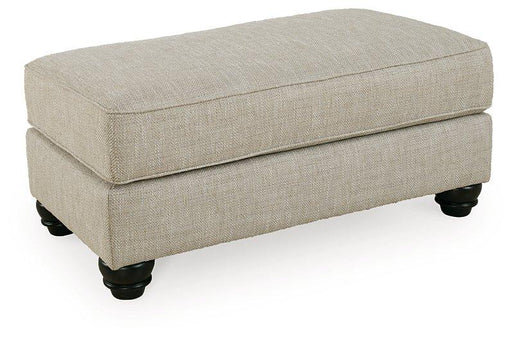 Ashanti ottoman by Ashley Furniture featuring a plush upholstered top and wooden legs in a modern living room setting