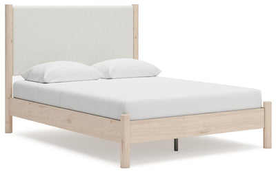 Ashley Furniture Cadmori upholstered bed with a plush headboard and neutral fabric, shown from an angled side view.