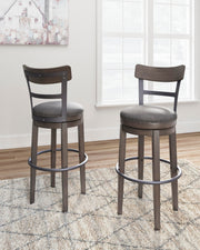 Ashley Furniture Caitbrook bar height bar stool with wooden frame and cushioned seat, shown in a modern home setting.