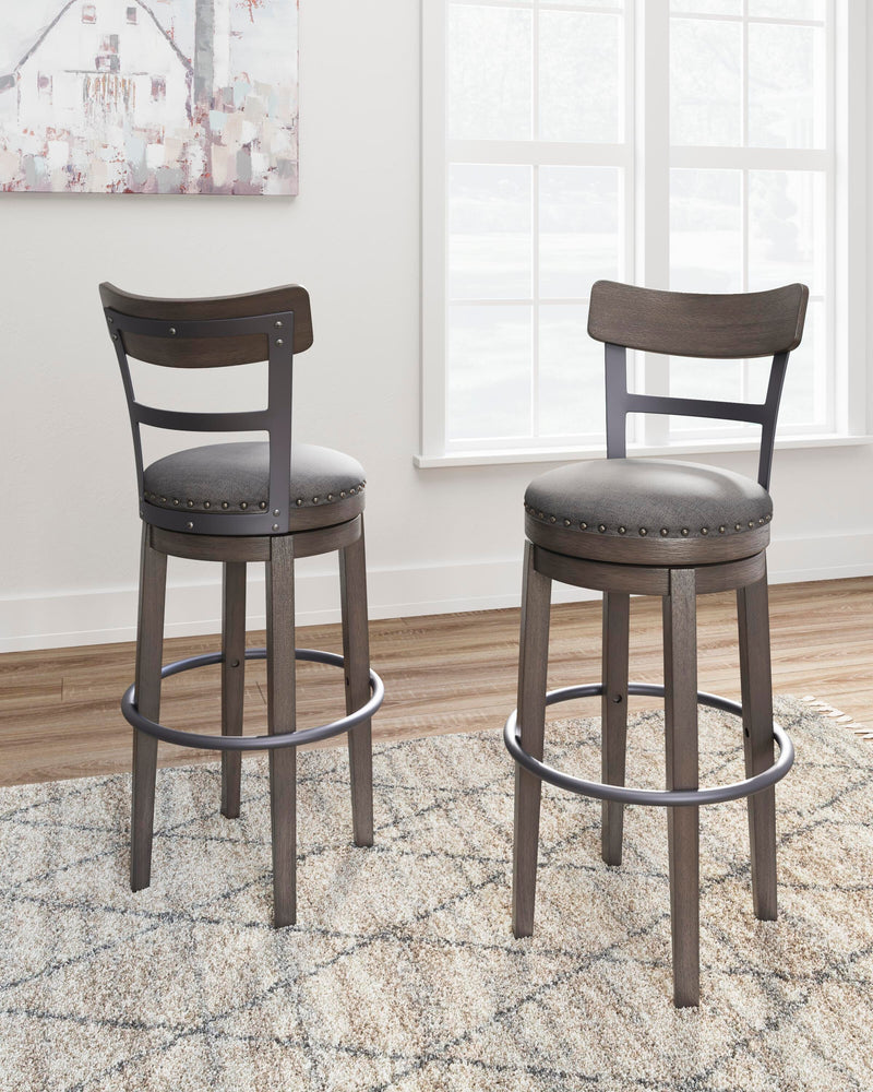 Ashley Furniture Caitbrook bar height bar stool with wooden frame and cushioned seat, shown in a modern home setting.